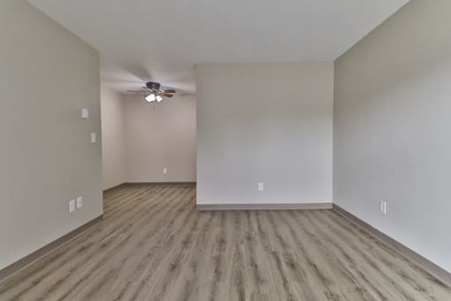 an empty living room with hardwood floors and a ceiling fan