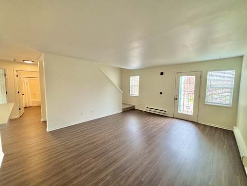 A room with wooden flooring and white walls.