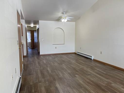 A long hallway with wood floors and white walls.