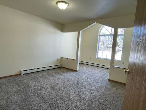 A room with a carpeted floor and a window.