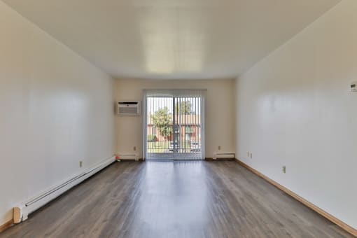 the living room of an apartment with wood flooring and a balcony