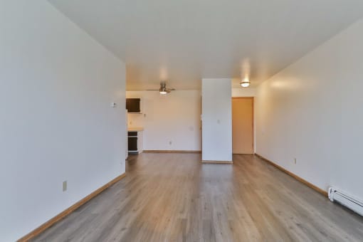 an empty living room with wood floors and white walls