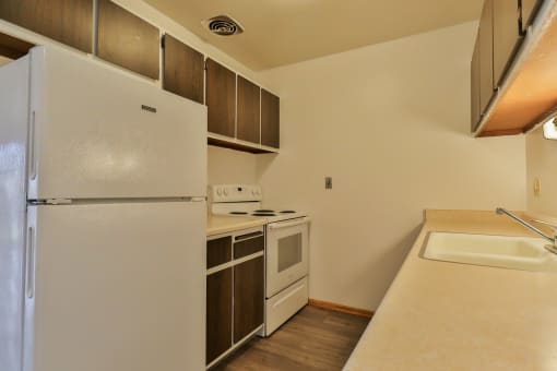 A white refrigerator is in a kitchen with a sink and stove.