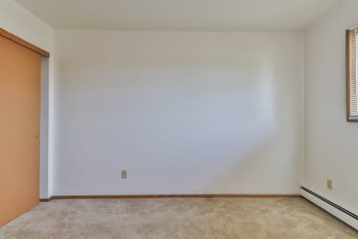 A room with a carpeted floor and a door on the left.