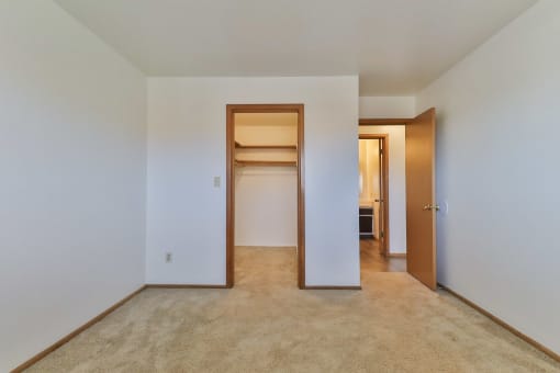 an empty bedroom with a walk in closet and a hallway to a bedroom