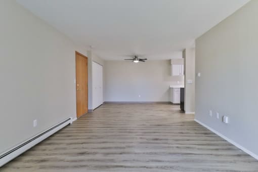an empty living room with wood flooring and a ceiling fan