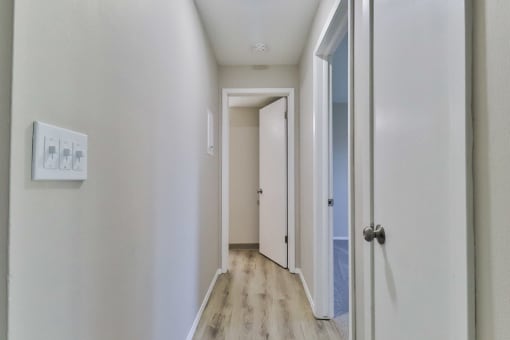 a hallway with white walls and wood floors and a white door