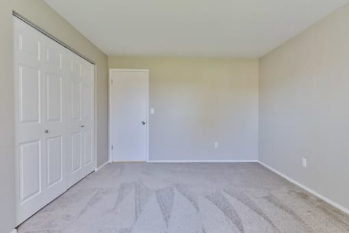 an empty bedroom with white walls and white doors