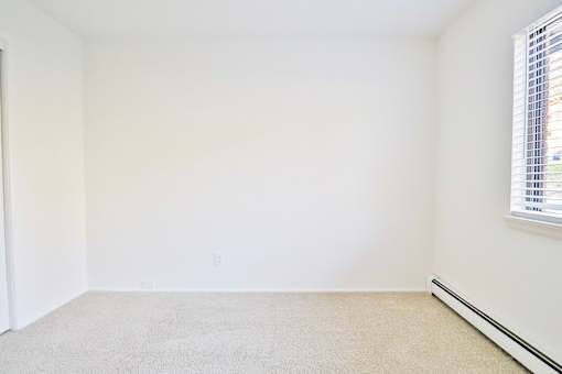 an empty room with white walls and two windows
