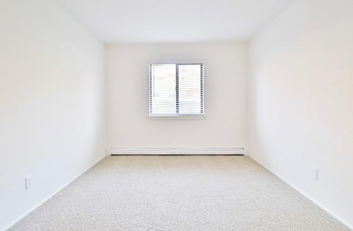 an empty room with a window and white walls