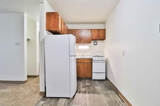 A white refrigerator is in a kitchen with wood cabinets.