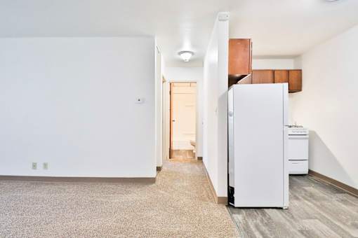 A white refrigerator sits in a kitchen next to a white wall.