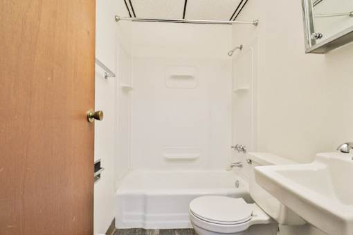A white toilet sits next to a white bathtub in a small bathroom.