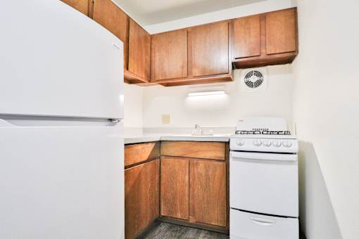 A white refrigerator is in a kitchen with wooden cabinets.