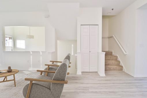 A living room with a grey chair and a staircase.