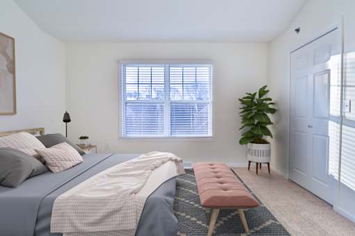A bedroom with a large bed and a window with blinds.