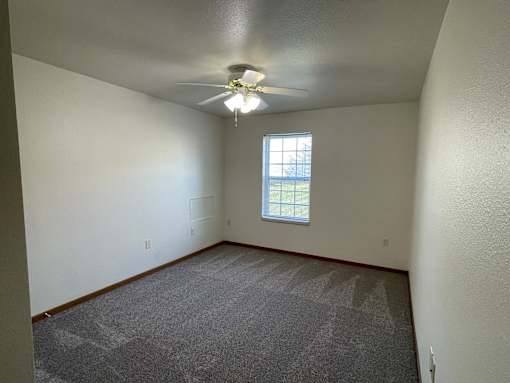 A room with a ceiling fan and a window.