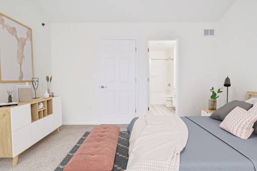 A bedroom with a bed, nightstand, and a dresser with a painting on top.