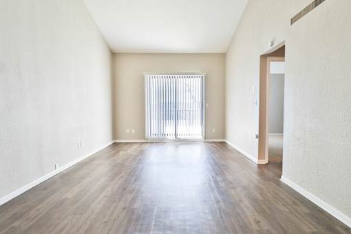 A room with wooden floors and a window with blinds.