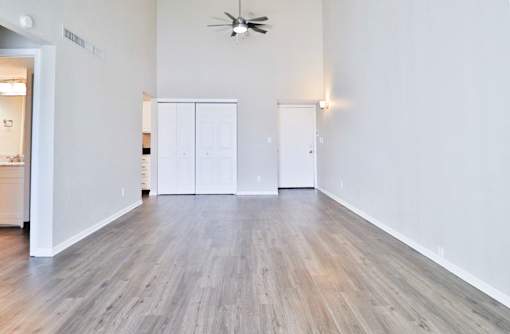 A room with a ceiling fan and wood flooring.