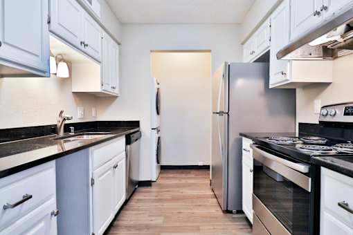A kitchen with white cabinets and a black countertop.