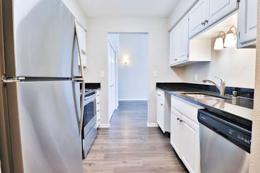 A kitchen with a refrigerator on the left and a sink on the right.