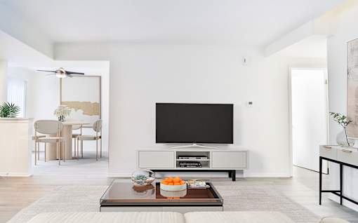 A modern living room with a flat screen TV and a glass coffee table.