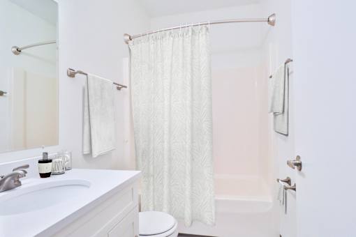 A white bathroom with a toilet, sink, and shower curtain.