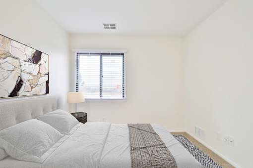 A bedroom with a large bed and a painting on the wall.