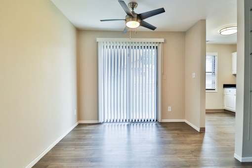 A room with a ceiling fan and a window with blinds.