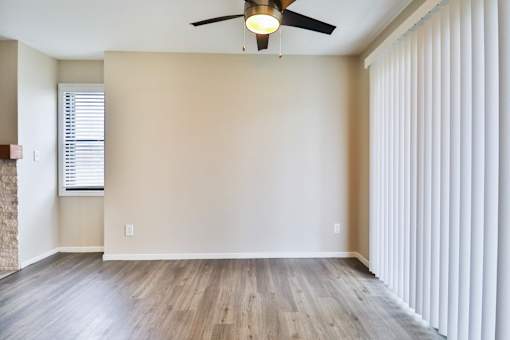 A room with a ceiling fan and a window with blinds.
