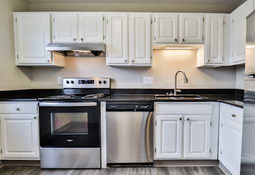 A modern kitchen with white cabinets and black countertops.