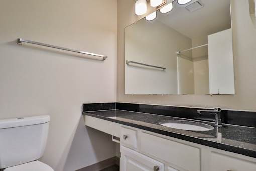 A bathroom with a toilet, sink, and mirror.