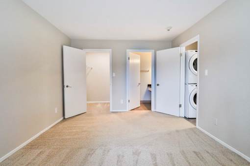 A room with a carpeted floor and three open doors.