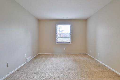 A room with a window and carpeted floor.