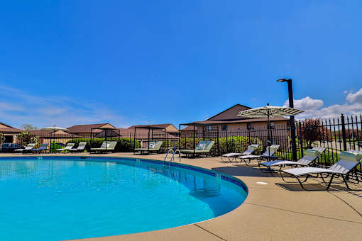 A swimming pool surrounded by lounge chairs and a fence.