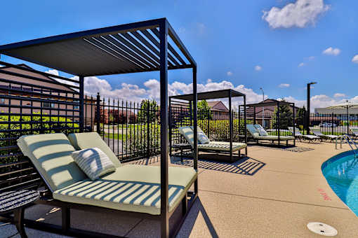 A poolside area with sun loungers and a metal fence.