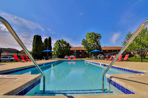 A swimming pool with a blue sky and trees in the background.