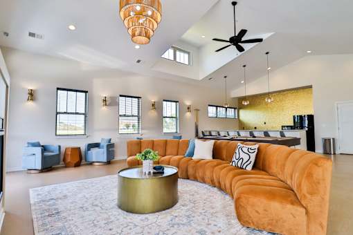 A living room with a large orange couch and a round gold coffee table.