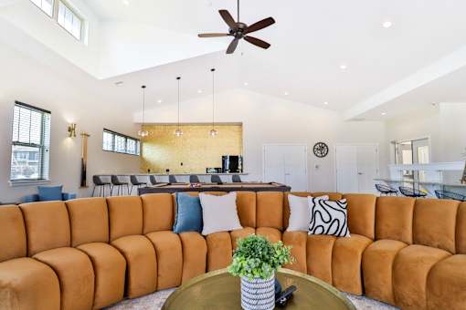 A living room with a brown sofa and a ceiling fan.