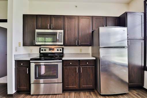 A modern kitchen with dark wood cabinets and stainless steel appliances.