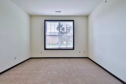 A room with a window and carpeted floor.