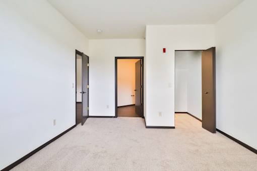 A white room with a carpet floor and three doors.