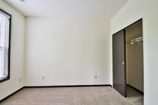A room with a carpeted floor and a door on the right side.