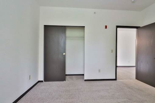 A room with a carpeted floor and three doors.