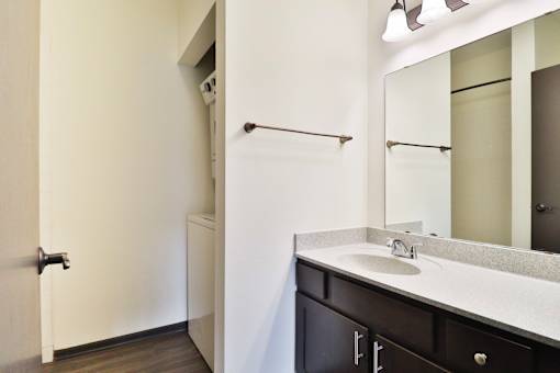 A bathroom with a sink, mirror, and towel rack.