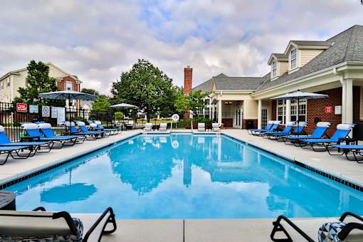 A large swimming pool with blue water and lounge chairs around it.