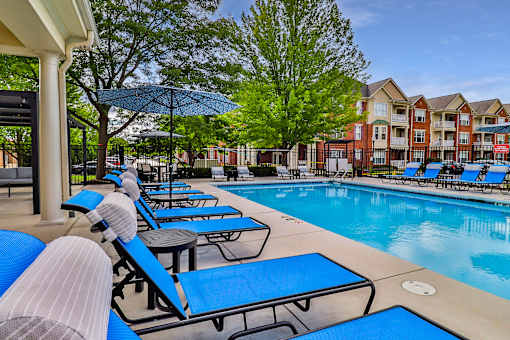 A pool area with sun loungers and a building in the background.