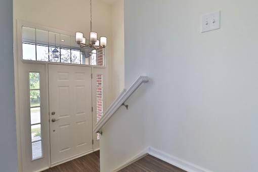 A white door with a window above it and a chandelier hanging from the ceiling.