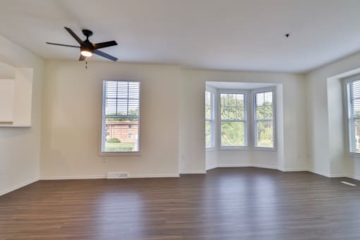A room with a ceiling fan and three windows.